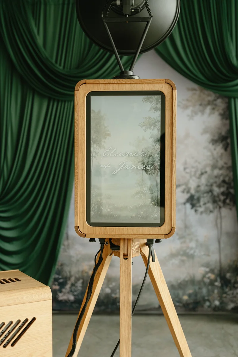 A personalised rear screen on the oak Icon Booth, framed by deep green drapes.